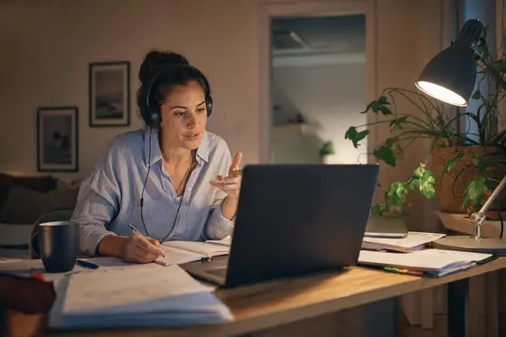 A woman on a video call at her desk, case documents spread around the laptop